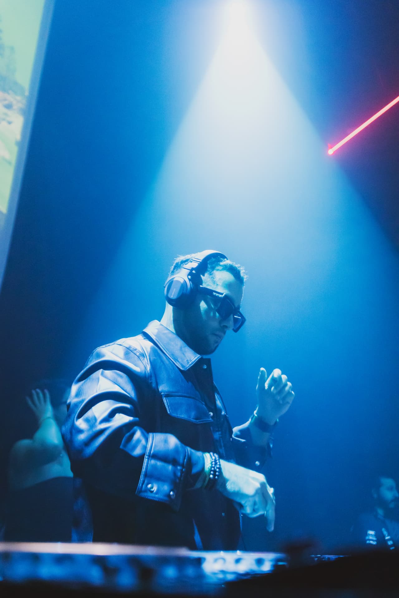 FARZY in a blue spotlight beam behind the decks